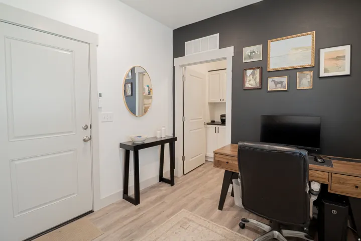 Wood-finish flooring throughout, white interior door, and dark accent wall