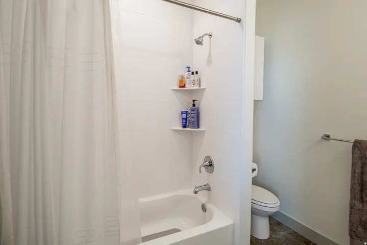 Bathtub-shower combination with chrome fixtures, integrated shelving, and white tile surround