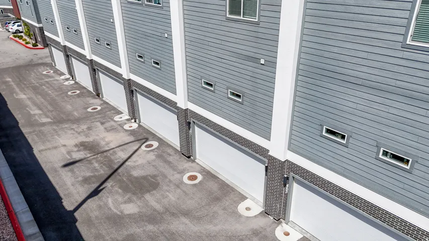 Gray horizontal siding with white trim, multiple garage doors, and brick detailing