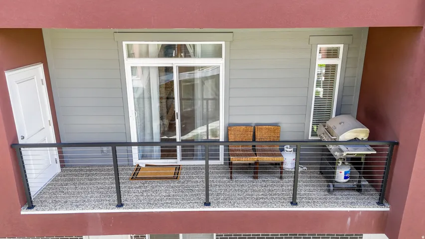 Balcony with cable railing, textured flooring, sliding glass door, and an exterior door