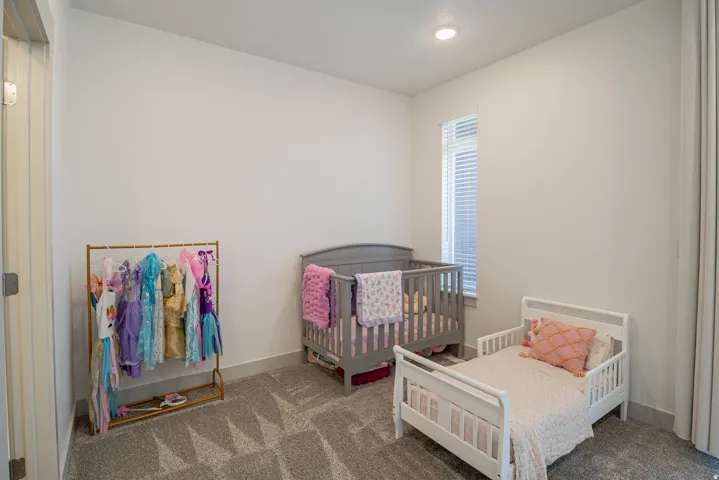 Recessed ceiling lighting, a narrow vertical window with blinds, and light gray wall paint