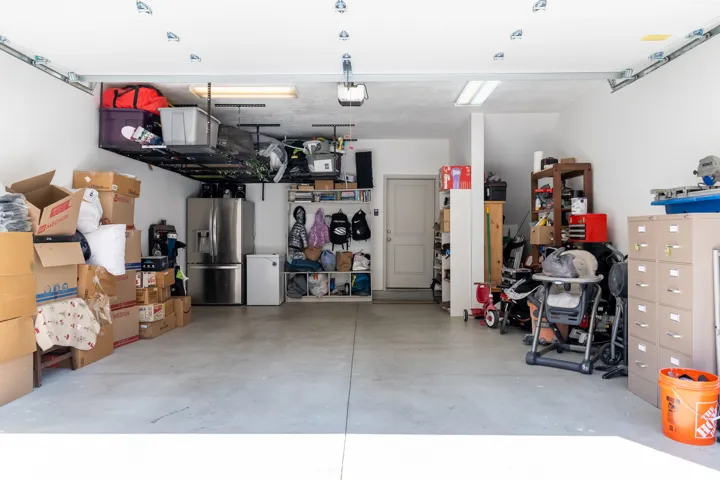Garage featuring concrete flooring, white walls, overhead storage racks, and recessed lighting