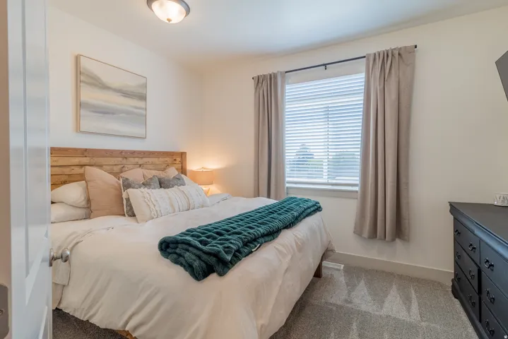 Recessed window with blinds and drapes, wood-panel headboard, wall-mounted light fixture, and carpet flooring