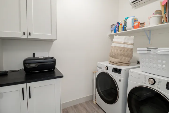 White shaker-style cabinetry with matte black hardware, black countertop, open shelving, and wood-finish flooring