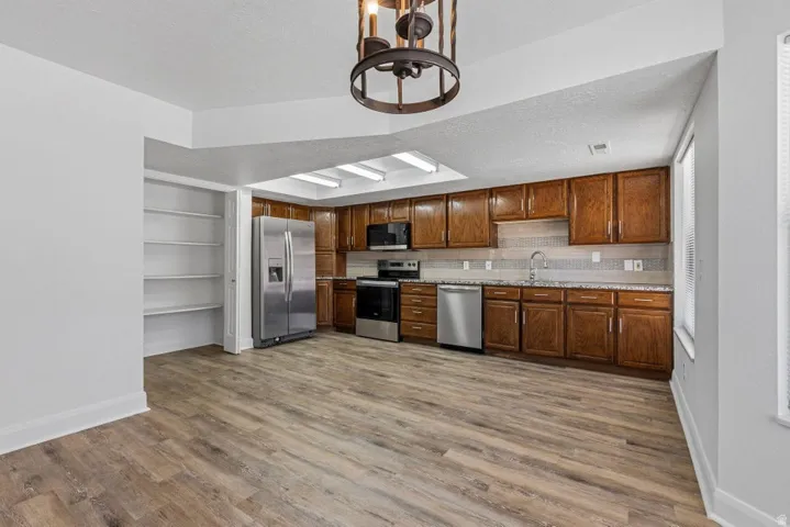 Kitchen featuring wood-finish flooring, recessed lighting, wood cabinetry, stainless steel appliances, and a tile backsplash