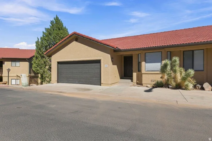 Stucco exterior with a terracotta tile roof, attached garage, and a concrete driveway