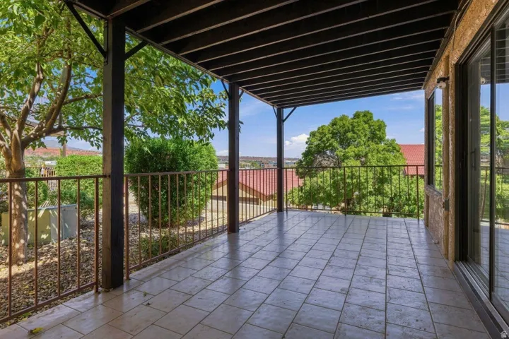 Spacious patio with tile flooring, protective overhead structure, and durable metal railing