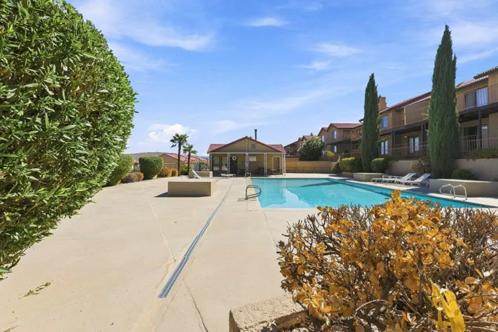Expansive outdoor pool area featuring a rectangular pool, concrete decking, and surrounding multi-story residential buildings