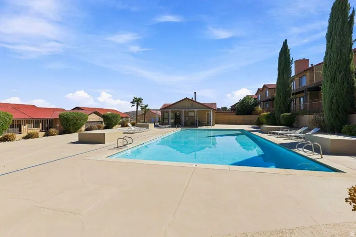 Rectangular swimming pool with integrated steps, surrounded by a spacious concrete deck and various foliage