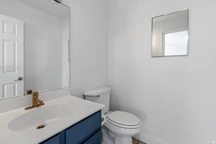 Vanity with a white countertop and integrated sink, gold-finish faucet, and blue cabinet storage