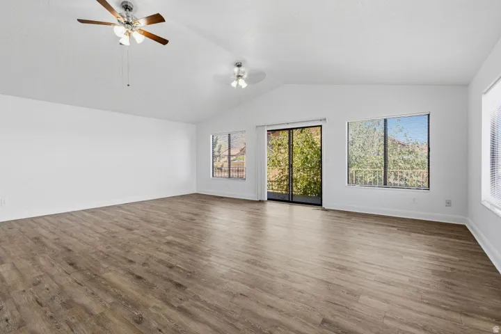 Vaulted ceilings, wood-finish flooring, multiple windows, sliding glass door, and two ceiling fans