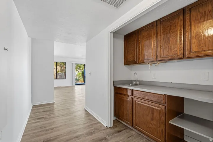 Wood-finish flooring, white walls, built-in cabinetry, and a countertop with an integrated sink