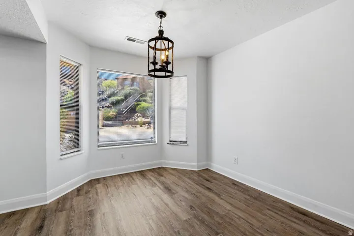 Wood-finish flooring, multiple windows with blinds, and a drum pendant light fixture