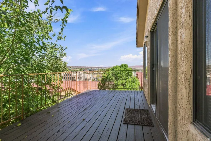 Expansive outdoor deck with wood-finish flooring, metal railing, and stucco exterior