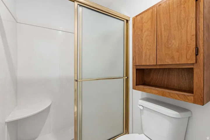 Shower enclosure with frosted glass door, built-in shower bench, and gold-finish frame