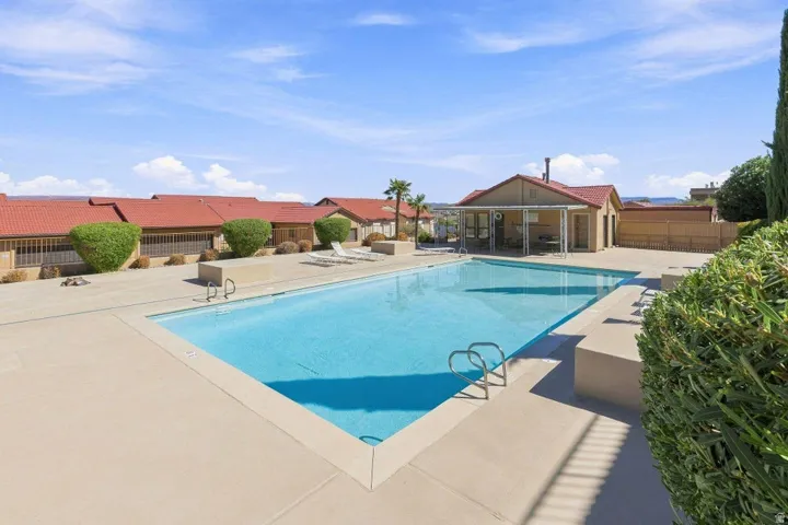 Outdoor swimming pool with integrated steps, concrete surround, and adjacent community building
