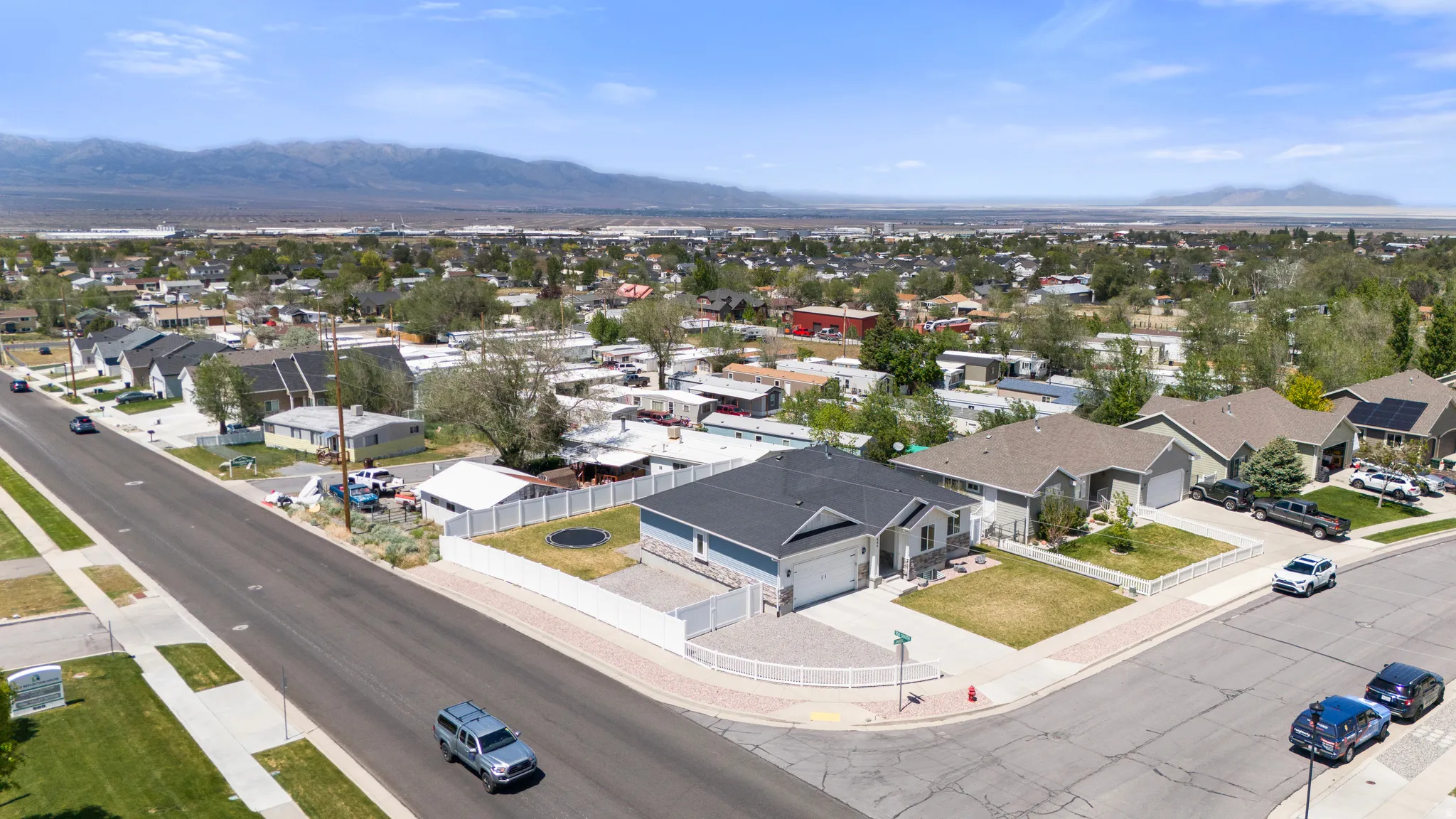 Corner lot residence featuring a two-car garage, fenced yard, and mountain backdrop
