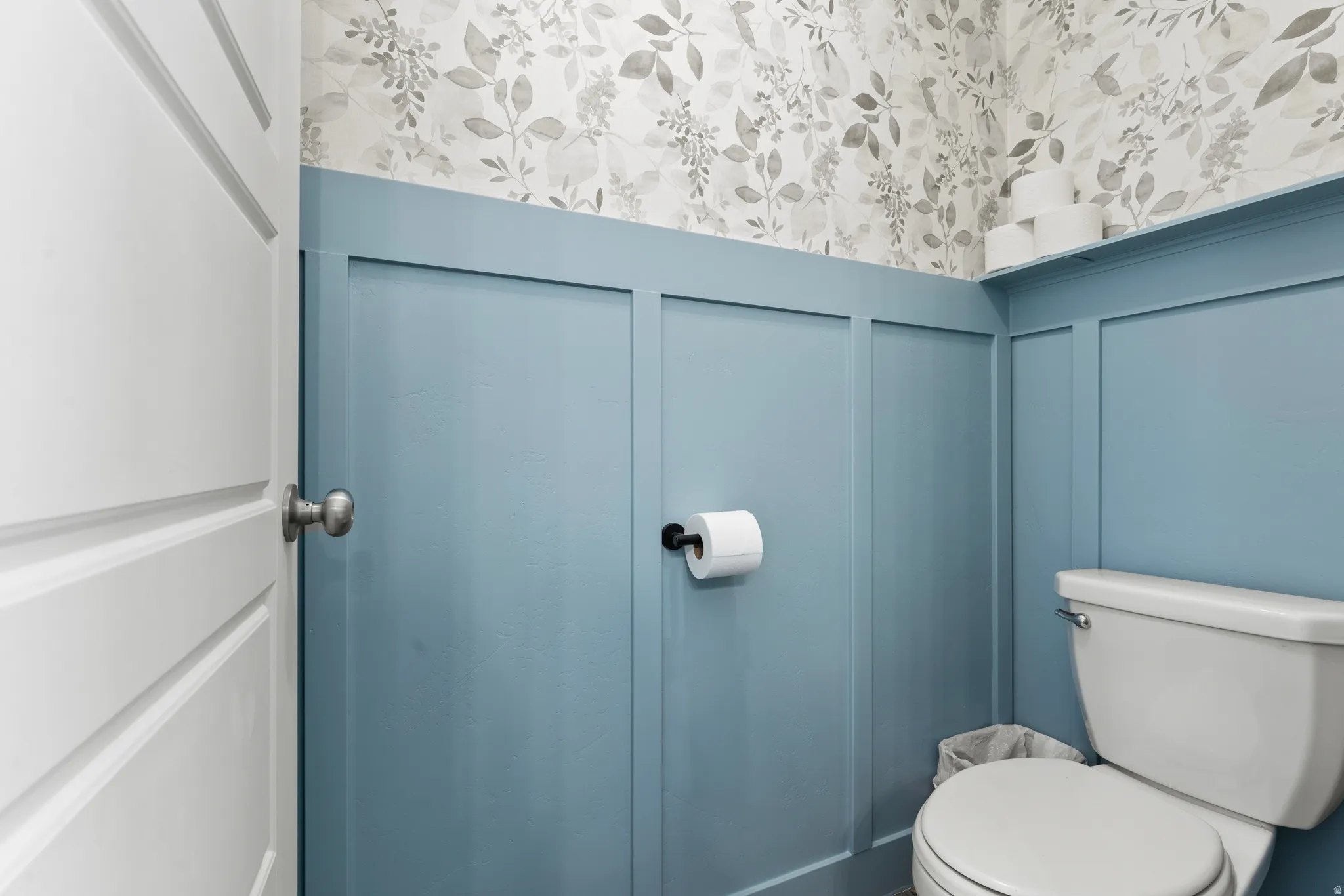 Wall-mounted toilet, decorative wallpaper, board and batten wall treatment, integrated wall shelf