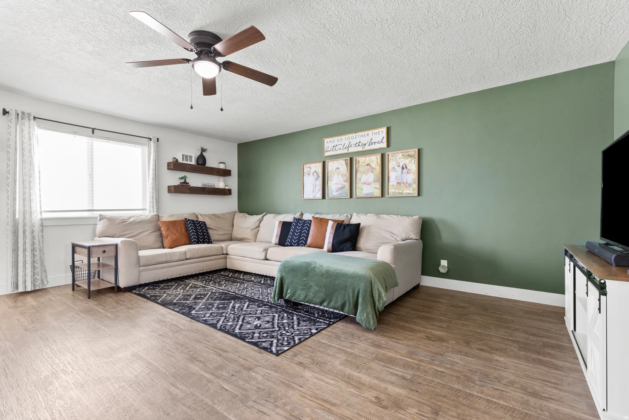 Recessed lighting, wood-finish flooring, ceiling fan with light fixture, built-in floating shelves, and window with blinds