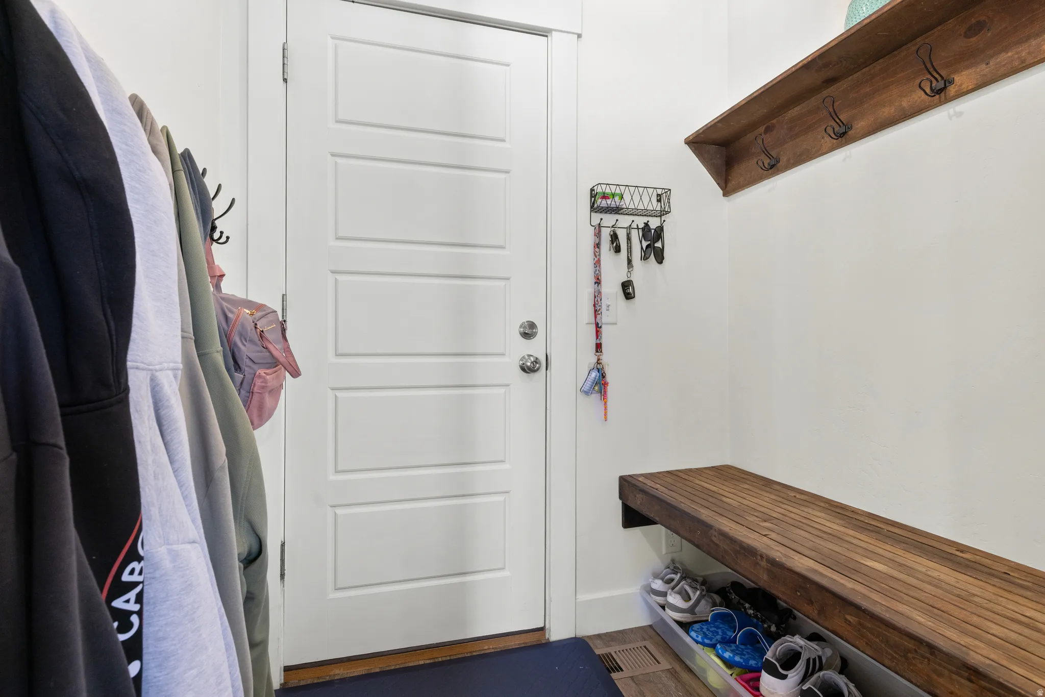 Built-in wood-finish bench, wood-finish shelving with coat hooks, and a white paneled door