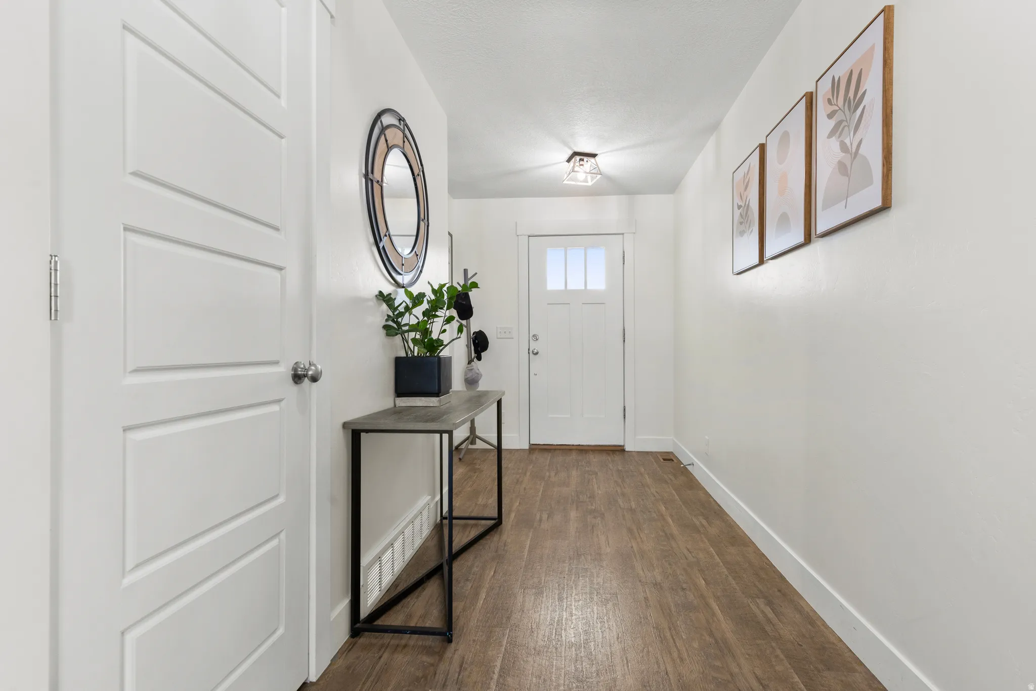 White interior doors, wood-finish flooring, white walls, flush mount lighting, and a front entry door with glass panels