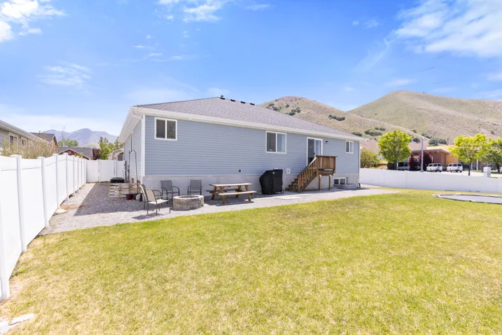 Expansive grassy yard with white privacy fencing, gravel patio area, and a wood deck