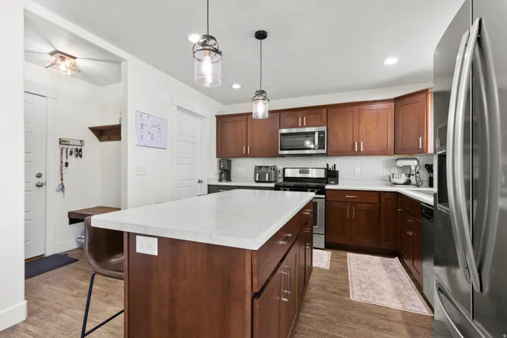 Kitchen featuring wood-finish flooring, a central island with a light-toned countertop, and dark wood cabinetry
