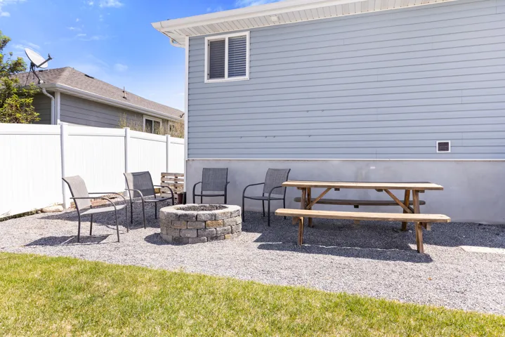 Gravel patio area featuring a stone fire pit and a privacy fence