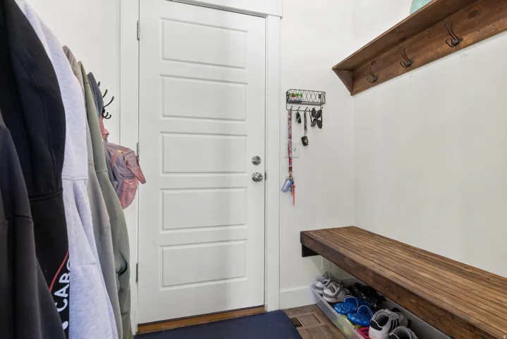 Built-in wood-finish bench, wood-finish shelving with coat hooks, and a white paneled door