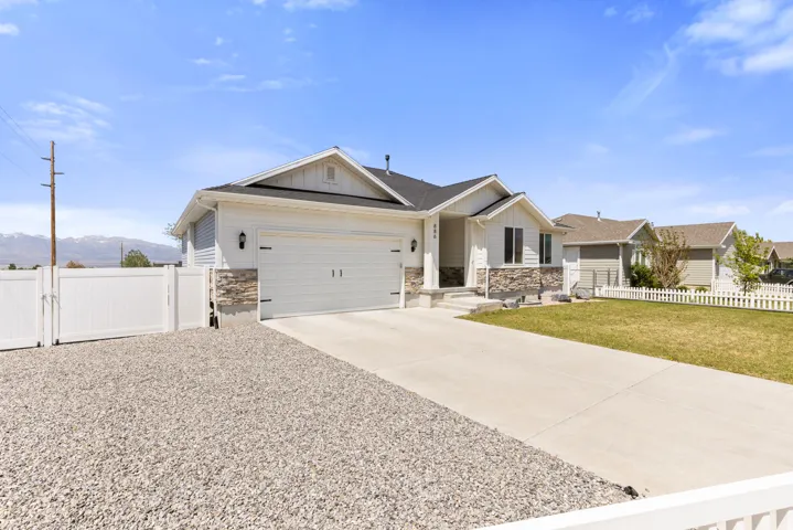 Modern ranch-style home featuring a two-car garage, stone façade accents, and a concrete driveway