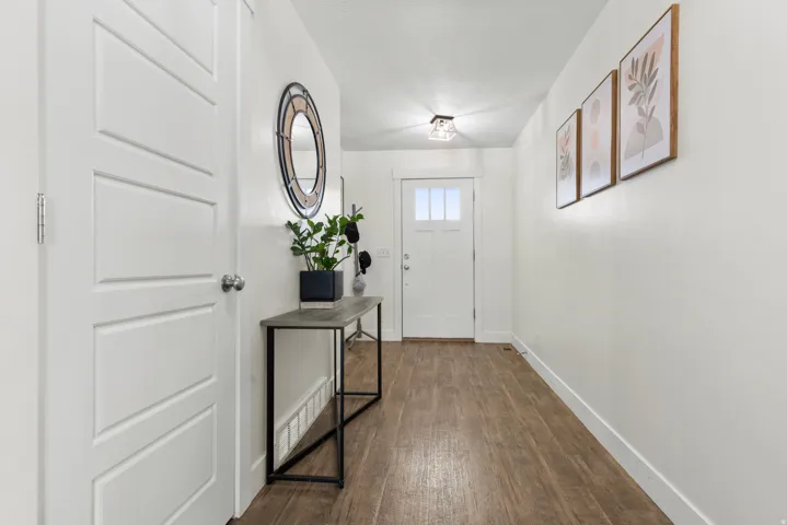 White interior doors, wood-finish flooring, white walls, flush mount lighting, and a front entry door with glass panels