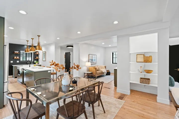 Open-concept living space with light wood-finish flooring, recessed lighting, and a built-in shelving unit