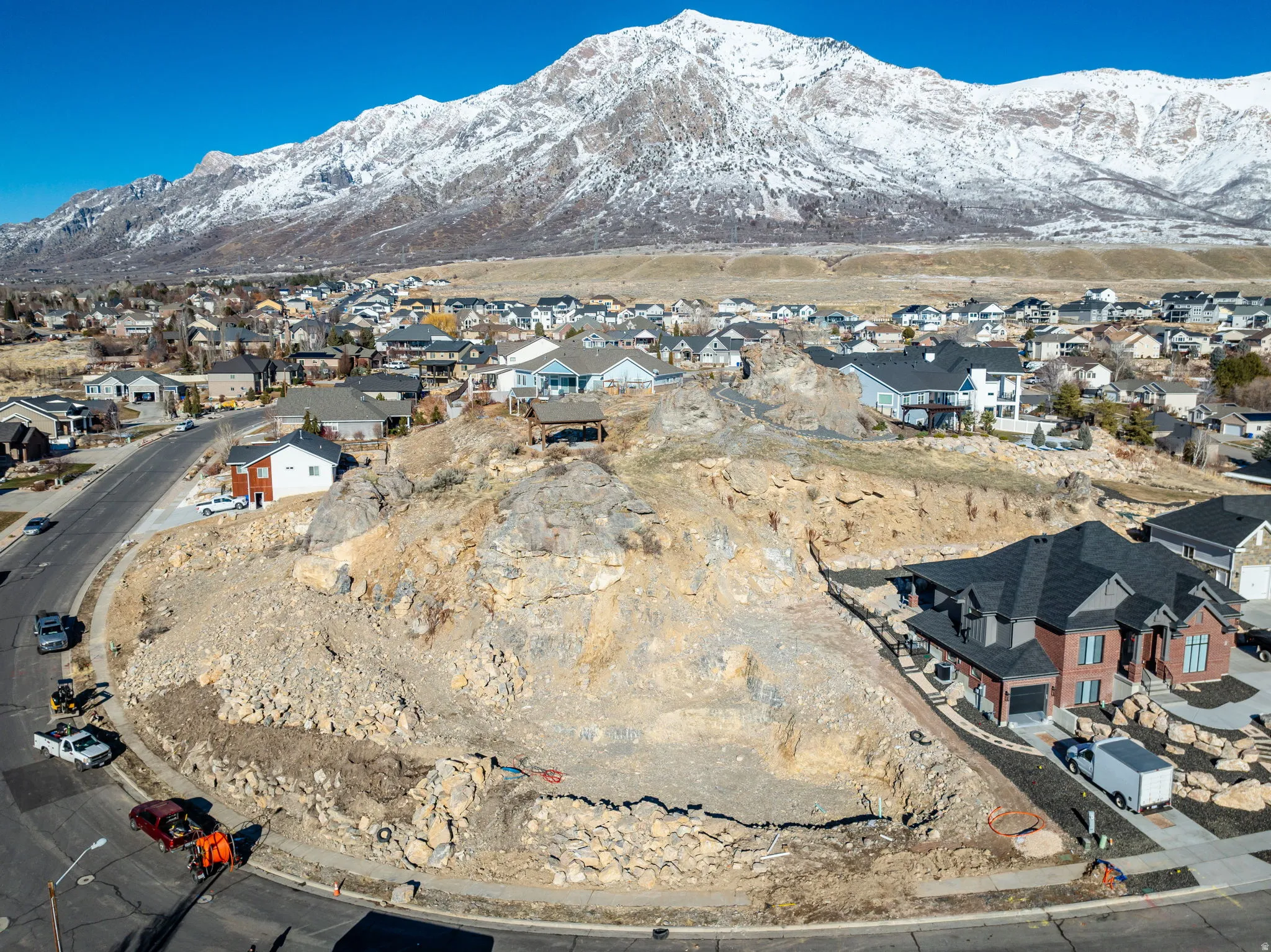 Mountain backdrop, residential neighborhood, paved road frontage, natural rock formations, surrounding homes