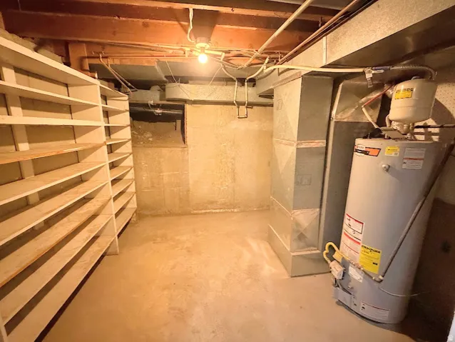 Extensive built-in shelving, exposed wood beams, concrete flooring, and water heater