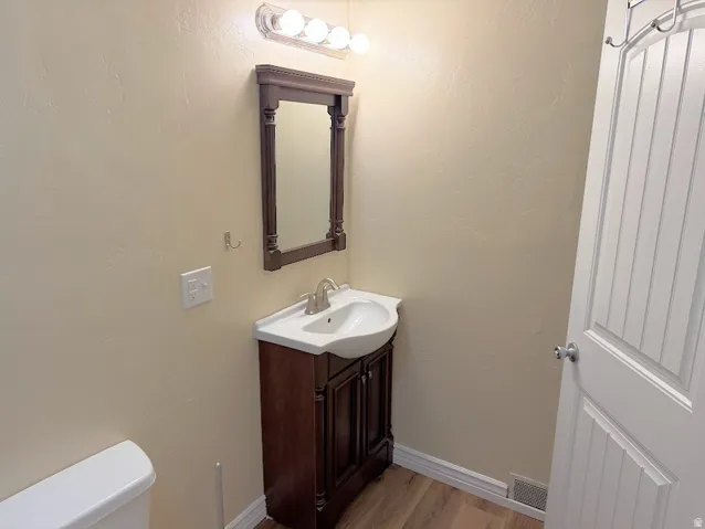 Pedestal sink with a dark wood-finish vanity and mirror