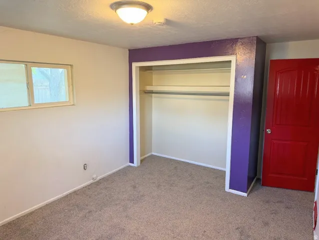 Wall-to-wall carpeting, built-in closet with hanging rod, and a semi-flush mount ceiling light fixture