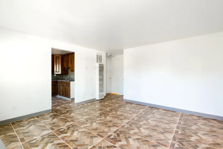 Spacious room featuring patterned floor tiling, white walls, and a built-in wall heater