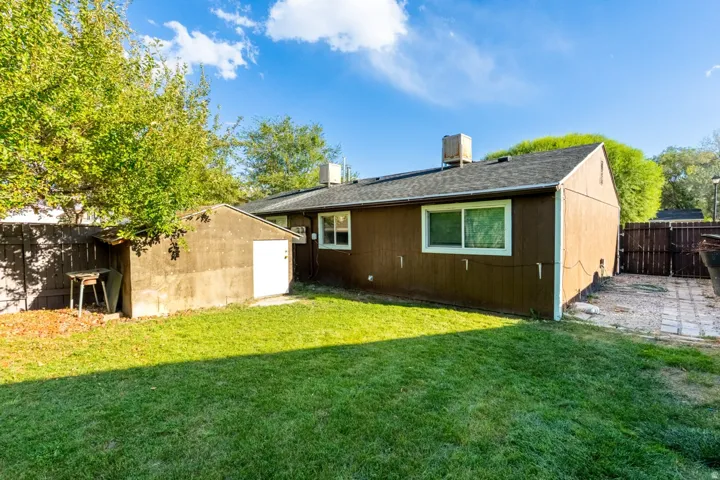 Expansive backyard featuring a manicured lawn, established trees, a fenced perimeter, and a detached storage shed