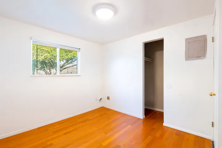 Hardwood flooring, recessed closet, modern flush mount ceiling light, white walls, and a window with horizontal blinds