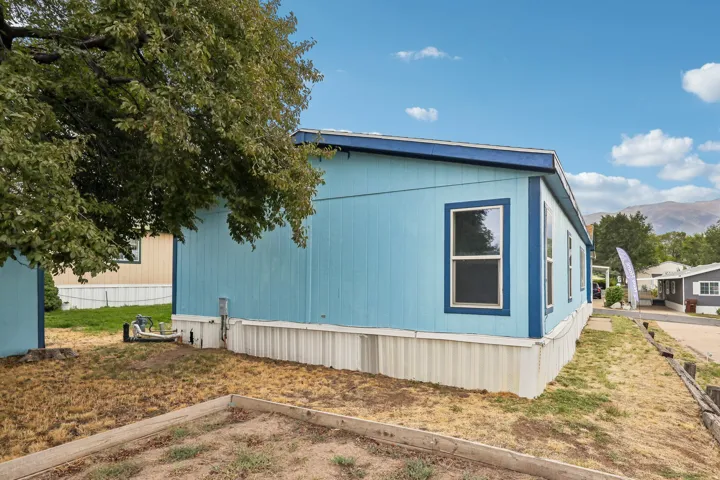 Light blue siding with blue trim, multiple windows, and a white foundation skirting