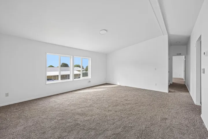 Spacious interior featuring neutral carpeting, white walls, and multiple windows