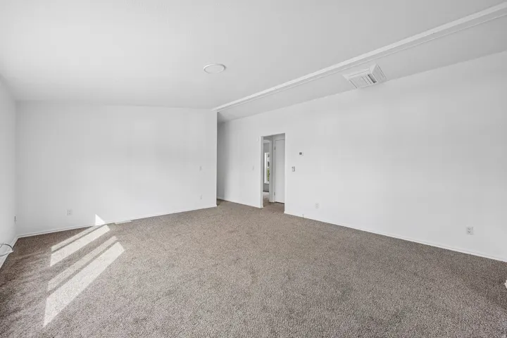 Expansive room with neutral carpeting, white walls, and a recessed ceiling light
