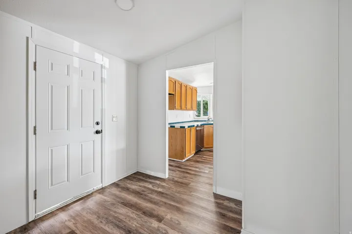 Wood-finish flooring, white paneled walls, and a white paneled door