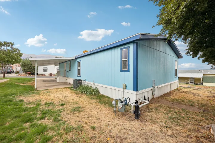 Light blue siding exterior with white trim and a covered carport