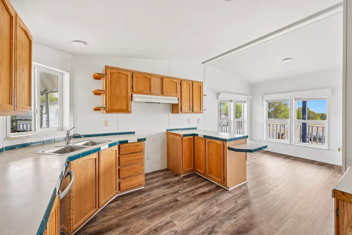 Wood-finish flooring, ample wood cabinetry, a double basin sink, and a countertop extension