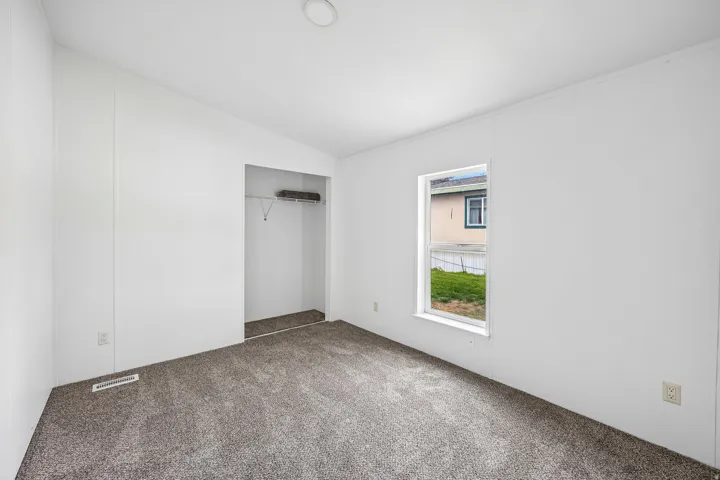 Neutral-toned carpeted flooring, white walls, and a single window