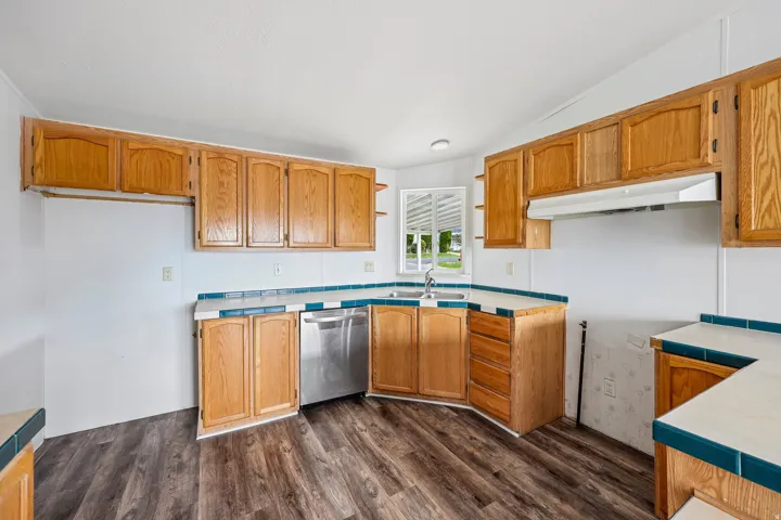 Wood-finish flooring throughout, complemented by wood cabinetry and stainless steel dishwasher