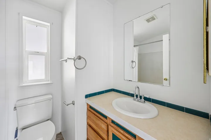White vanity with a laminate countertop, oval sink, and chrome faucet