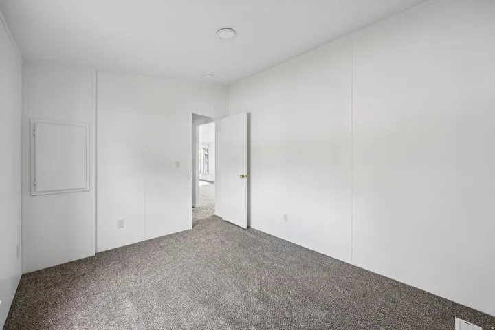 Neutral wall tones, recessed lighting, and grey carpet flooring