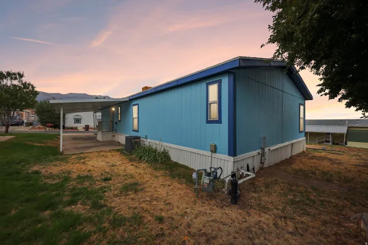 Light blue siding with dark blue trim, elevated foundation, covered carport, and concrete driveway